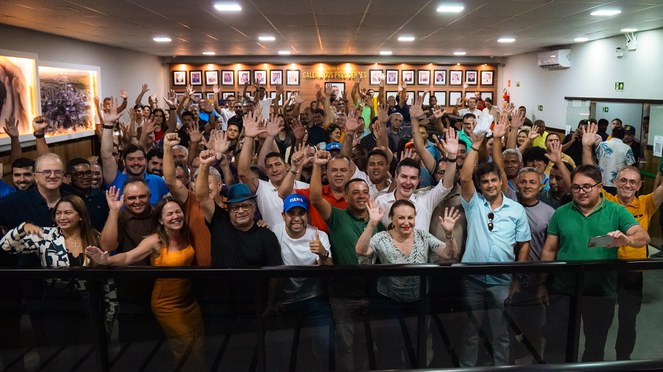 Grupo de pessoas comemorando a assinatura de casas habitacionais. 